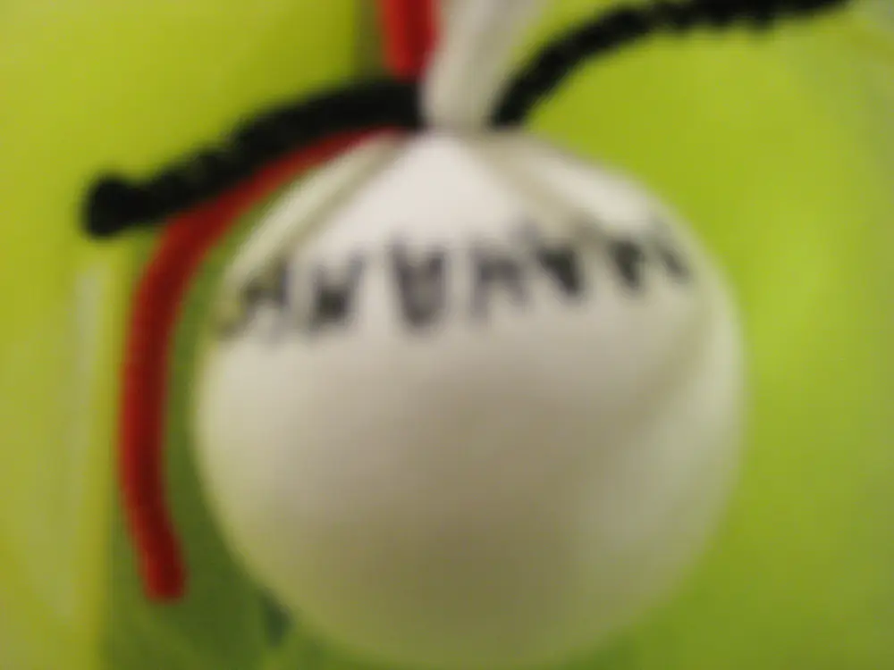 A blurry photo showing the same craft ball from the other side, with black letters that are hard to make out.