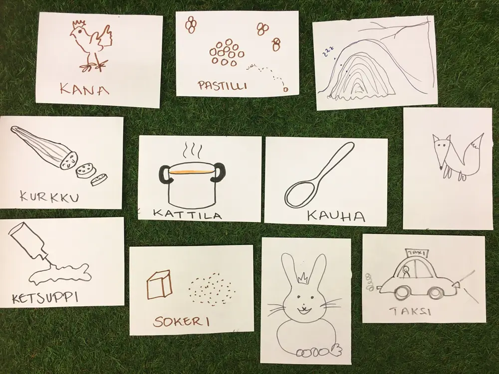 A collection of simple hand-drawn illustrations on small sheets of paper, each featuring a drawing and a descriptive word in Finnish. In the centre of each illustration are a cooking pot and a ladle, surrounded by a chicken, pastilles, a cave, a fox, a taxi, a bunny, sugar, ketchup, and a cucumber.