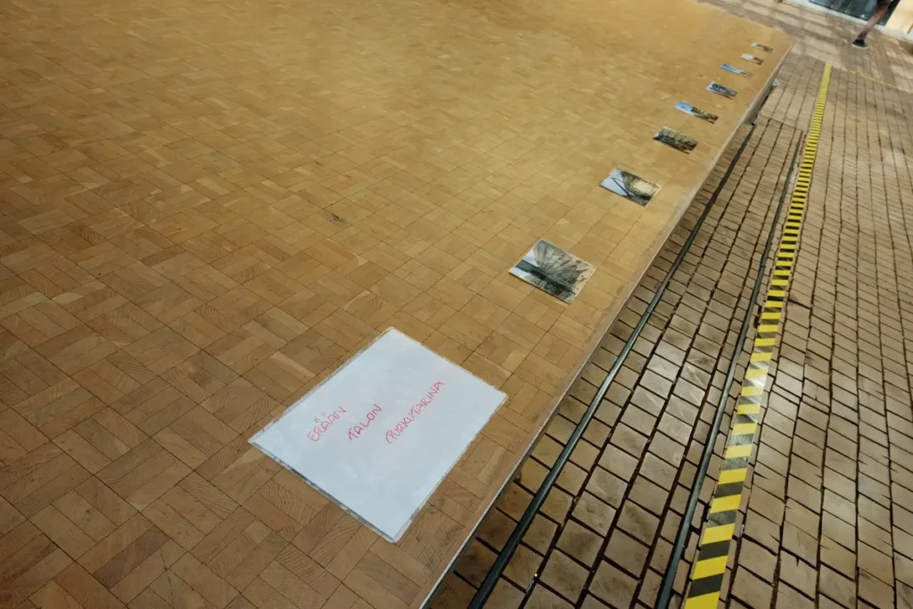 A photograph of the photographs attached to the floor of the stage, starting with a text: The story of a house being demolished.
