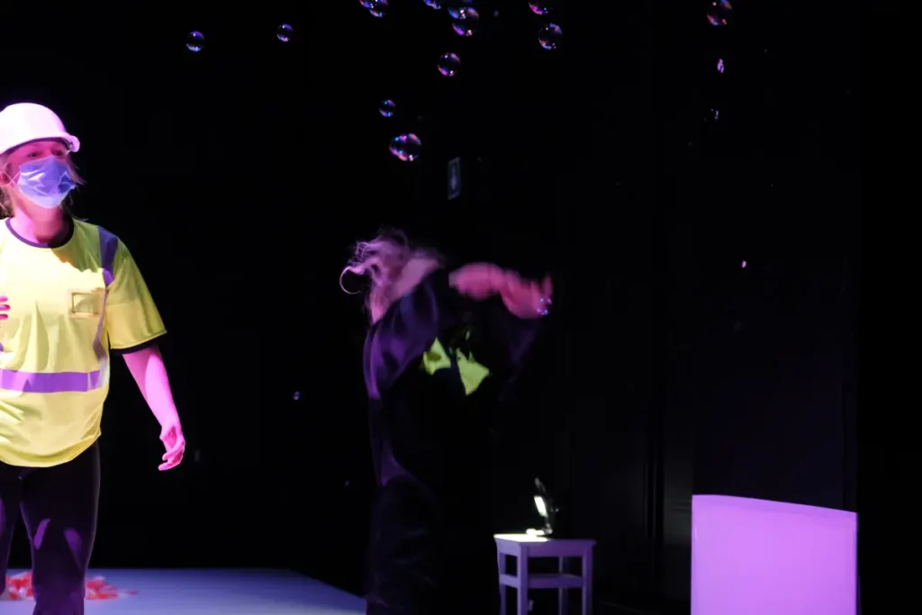 A collage of two photographs shows a child and an adult dancing in a room with purple lighting, with soap bubbles floating in the air. On the left, the adult is bending towards the floor, and the child has thrown themselves onto the floor on their back. On the right, the child is trying to catch the bubbles.