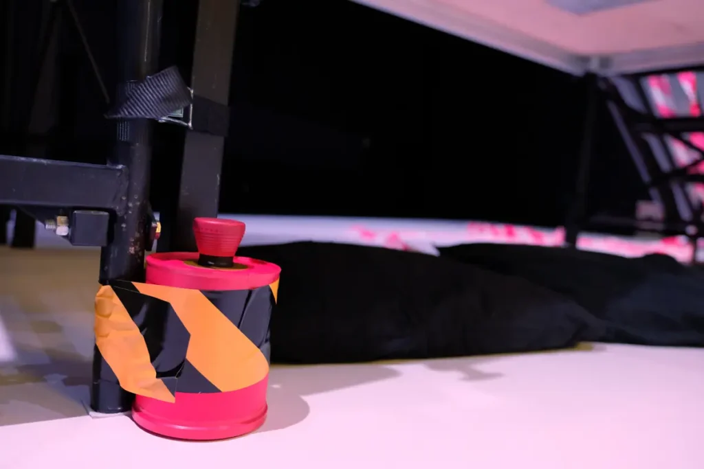The photograph shows a red cylinder on the floor with a red button for triggering an explosion.