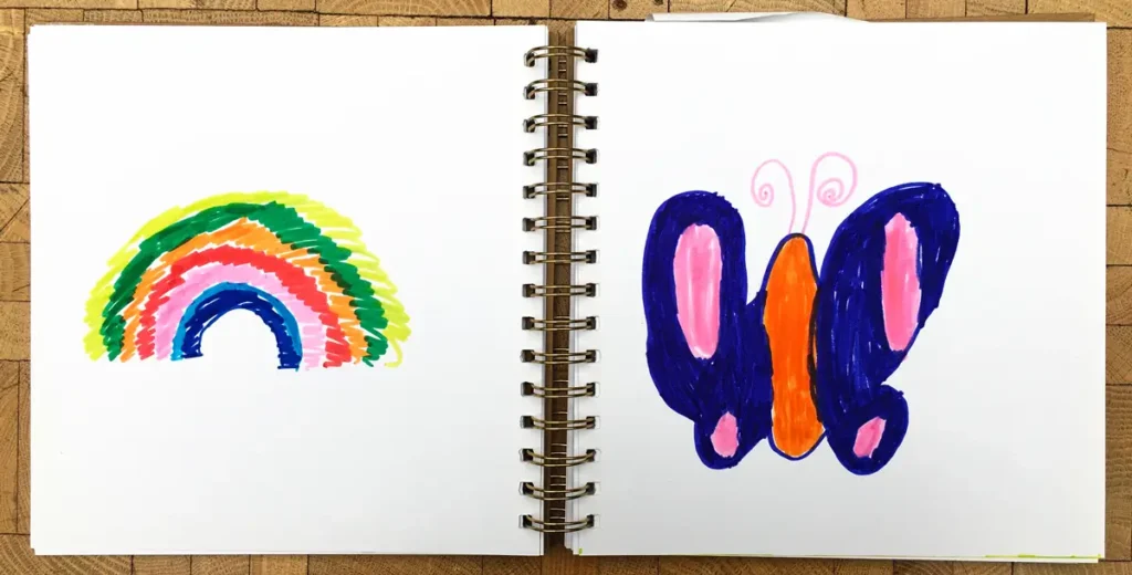 The photos show pages from the guestbook featuring drawings related to swinging. They include colourful drawings, such as a rainbow and a butterfly, along with the text &ldquo;What was fun: In the swing.&rdquo;